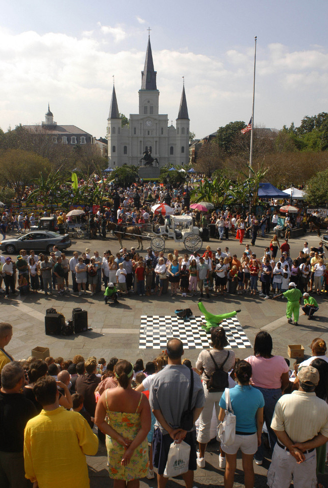 Visitors taking in a street performance in New Orleans with the cathedral in the background.