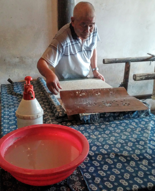 A local resident practicing the traditional method of dying blue silk at the Indigo Fabric shop.
