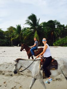 Jared horseback riding on the beach with his wife.